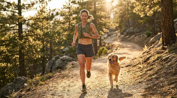 Woman trail running with a dog in a mountain landscape